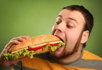 Мужчина ест большой бутерброд